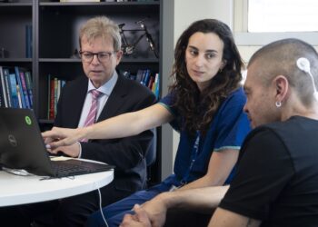 (From left) Chief investigator, ENT surgeon Professor Stephen O’Leary from The Royal Victorian Eye and Ear Hospital and cochlear implant fellow Dr Phoebe Ramos demonstrating Hear Alert to cochlear implant recipient Sean Kelleher from Bendigo.  Image: The Royal Victorian Eye and Ear Hospital.